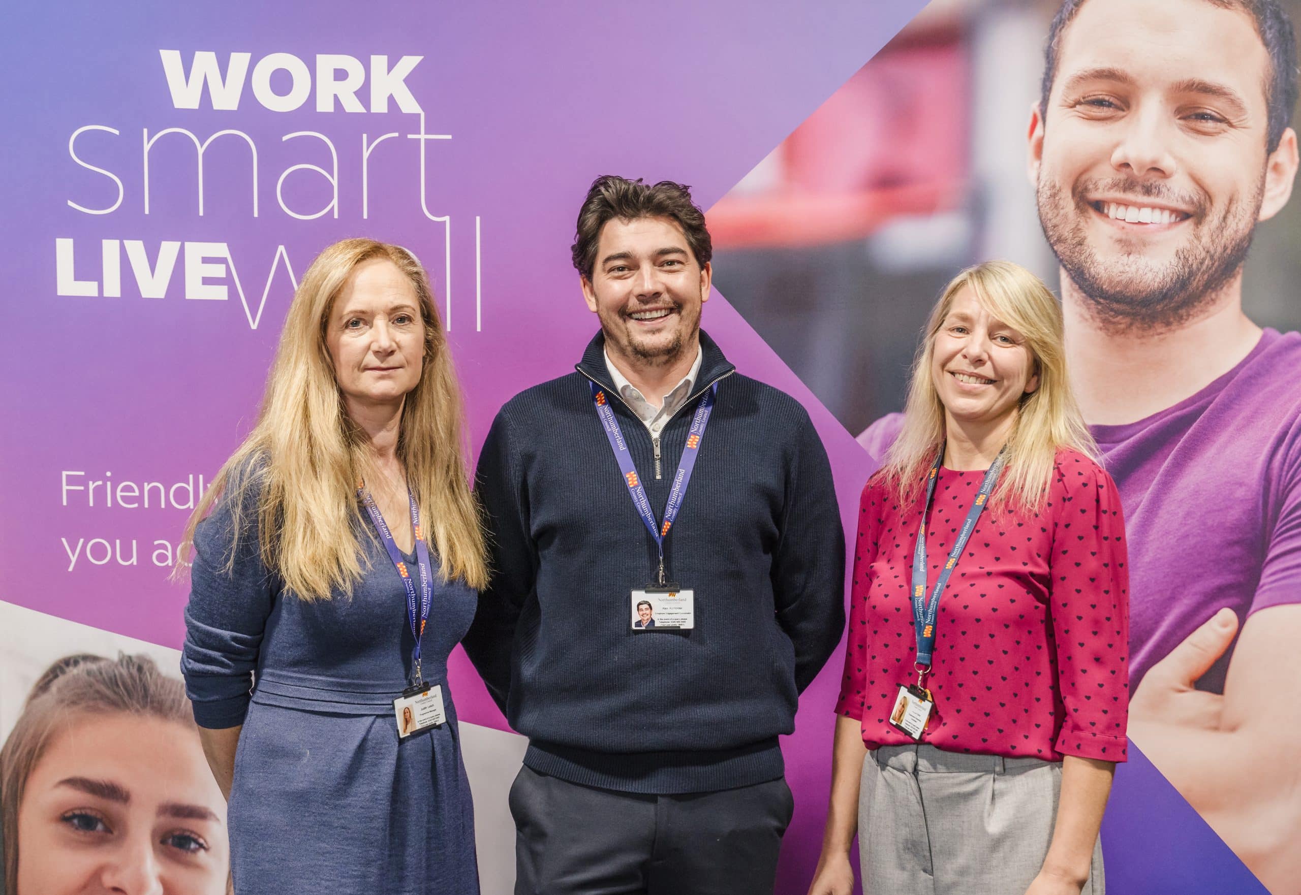 Three people stood in front of Work smart live well signage